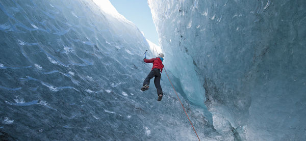 Woman climbing out of glacier cave / sólheimajökull glacier in iceland