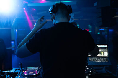 Rear view of dj playing music in club