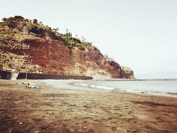 Rock formations on beach against clear sky