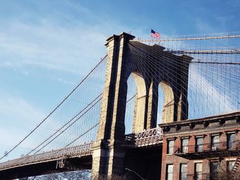 Low angle view of suspension bridge against cloudy sky brooklyn bridge