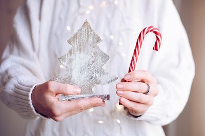 Midsection of woman holding christmas tree and candy cane