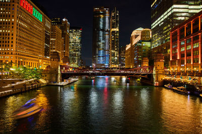 Illuminated bridge over river in city at night