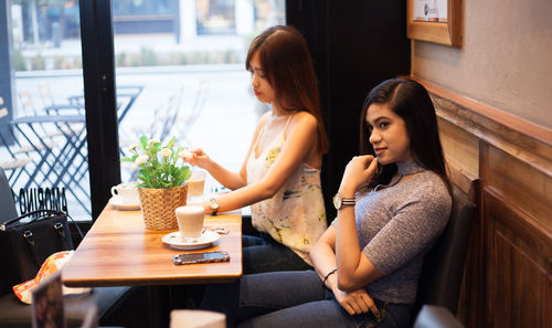 Young woman sitting on table at restaurant