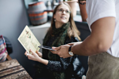 Female customer asking from menu to waiter holding digital tablet at restaurant