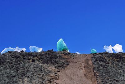 Low angle view of rocks against clear blue sky