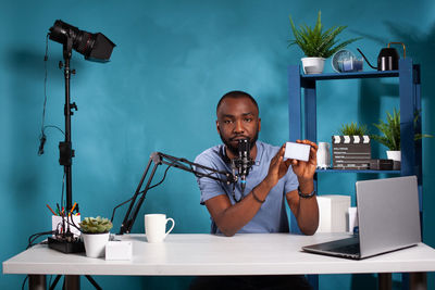 Young man using mobile phone while sitting on table