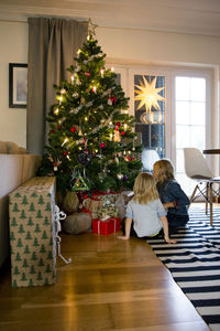 Girls sitting in front of christmas tree