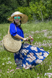 Woman with pink flowers in basket on field