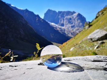 Close-up of crystal ball on rock against sky