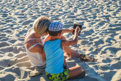 Rear view mother and son taking selfie at beach