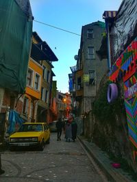 Rear view of people on street amidst buildings in city