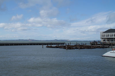 Pier on sea against cloudy sky