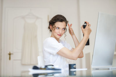 Woman at home doing her hair with hairspray