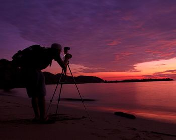 Photographer photographing sea during sunset