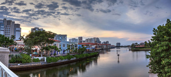 Buildings by river against sky in city