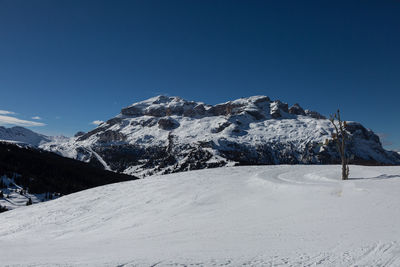 Scenic view of snow covered mountains against clear blue sky