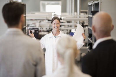 Female engineer explaining business people in manufacturing industry