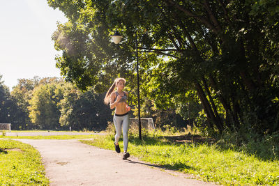 Full length of woman standing on grass against trees