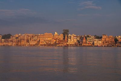 Scenic view of sea by cityscape against sky