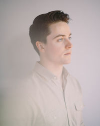 Portrait of young man looking away against white background