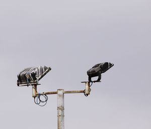 Low angle view of floodlights against sky  