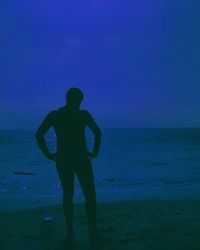 Rear view of silhouette man standing at beach against sky