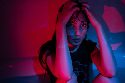 Depressed asian woman suffering from alcohol or drug addiction in bathroom under red neon light