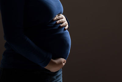 Midsection of woman standing against black background