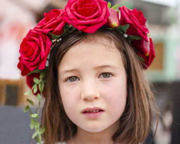 Portrait of a serious little girl with a wreath of roses in her hair