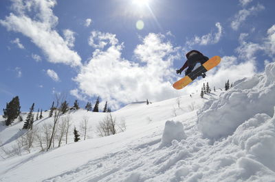 Low angle view of person snowboarding on snowcapped mountain against sky
