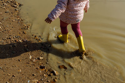 Low section of woman walking on sand at beach