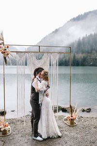 A happy couple in love and married embrace in nature by the lake and the misty mountains