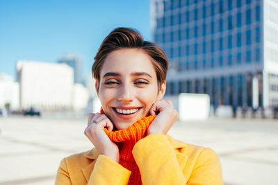 Portrait of young woman looking away while standing in city