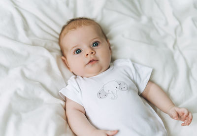 Cute baby girl 2-4 month on the bed with white linen, natural tones, selective focus