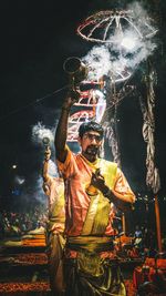 Statue of man holding illuminated sculpture at night