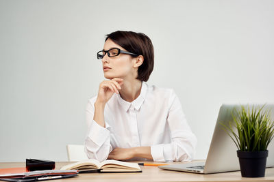 Young woman using mobile phone while sitting on table