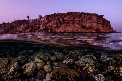 Rock formations by sea against clear sky