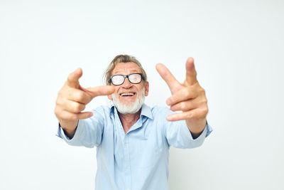 Portrait of smiling senior man gesturing against white background
