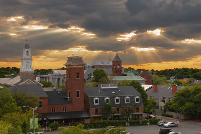 Houses and buildings in city against sky during sunset