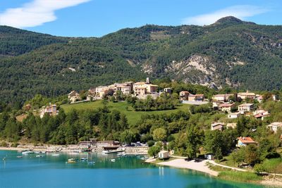 Scenic view of townscape by mountain against sky