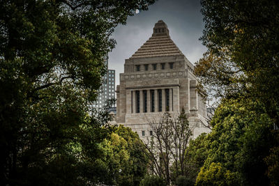 Low angle view of trees and building against sky