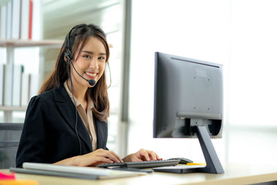 Young woman using mobile phone while sitting on table