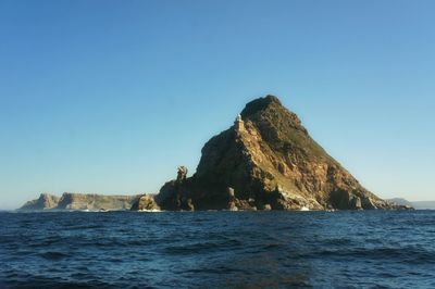 Rock mountain at sea against sky