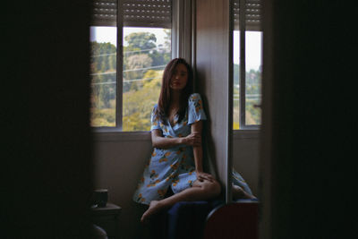 Portrait of woman sitting in window at home