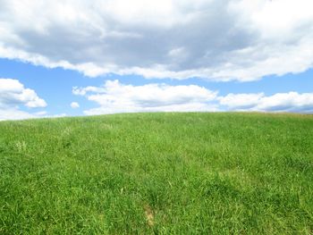 Scenic view of grassy field against cloudy sky