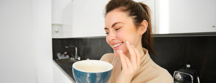 Side view of young woman drinking coffee at home