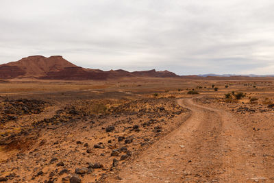 Dirt road in desert against sky