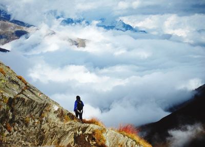 Man standing on mountain against cloudy sky