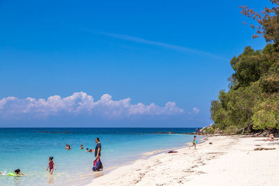 People on beach against blue sky