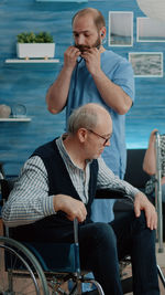 Male nurse standing by patient sitting on wheelchair at clinic